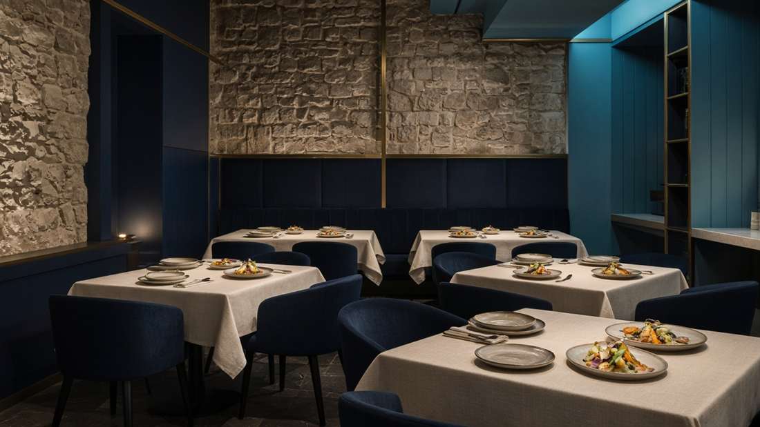 Salle du restaurant NicolCuisine, tables nappées et assiettes de légumes rôtis.